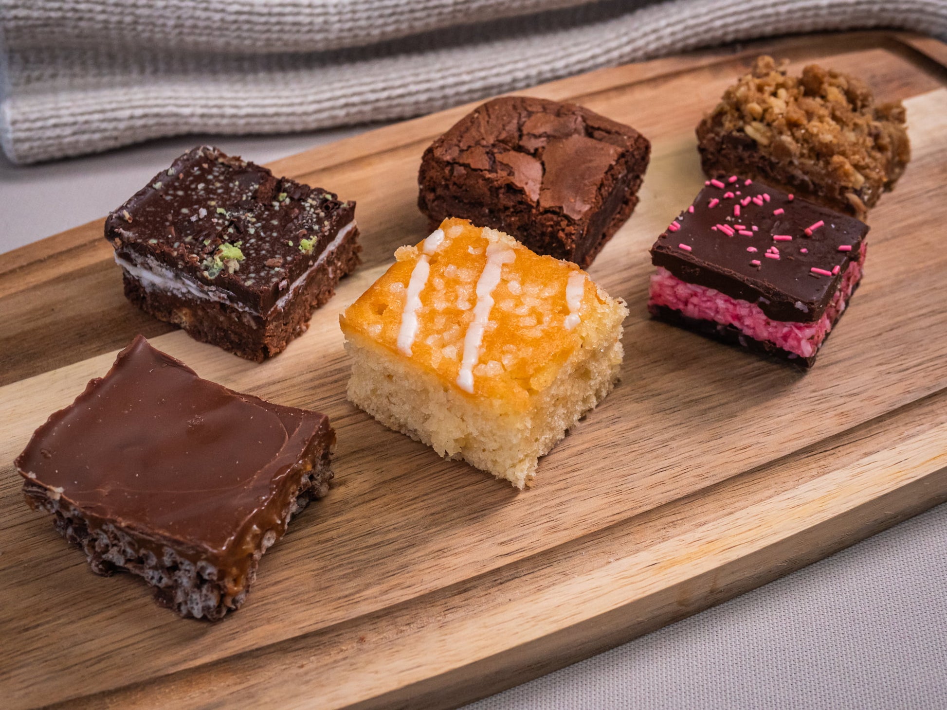 The Sub Side Assorted TrayBake Box features 24 pieces of house favorites like chocolate brownie bars and layered dessert squares, beautifully arranged for the perfect dessert platter.
