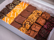 The Sub Side Assorted TrayBake Box (24 pieces) offers a selection of house-favorite dessert bars—chocolate brownie squares, lemon bars, and crumble-topped treats—neatly arranged for the perfect dessert platter.