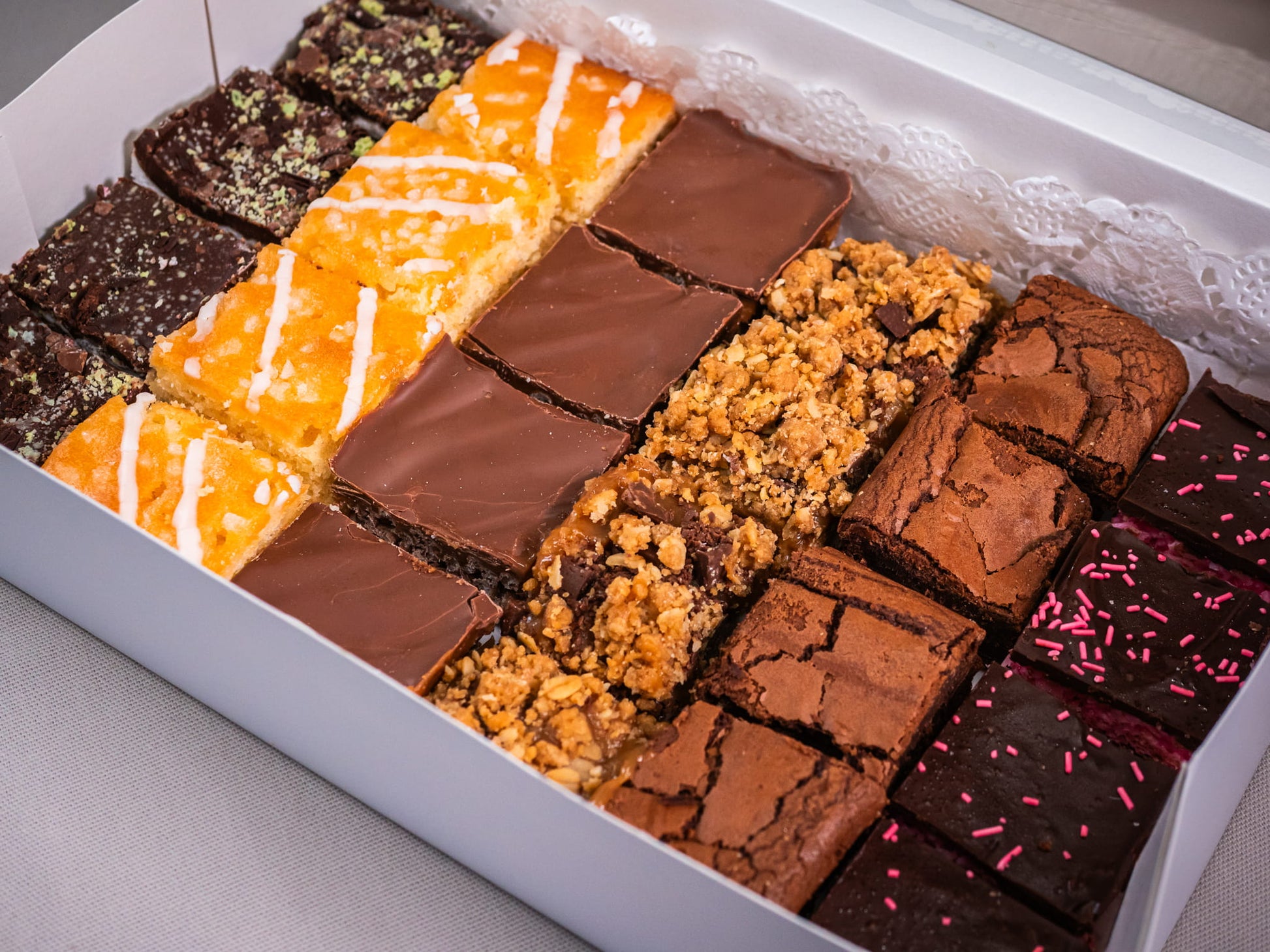 The Sub Side Assorted TrayBake Box (24 pieces) offers a selection of house-favorite dessert bars—chocolate brownie squares, lemon bars, and crumble-topped treats—neatly arranged for the perfect dessert platter.