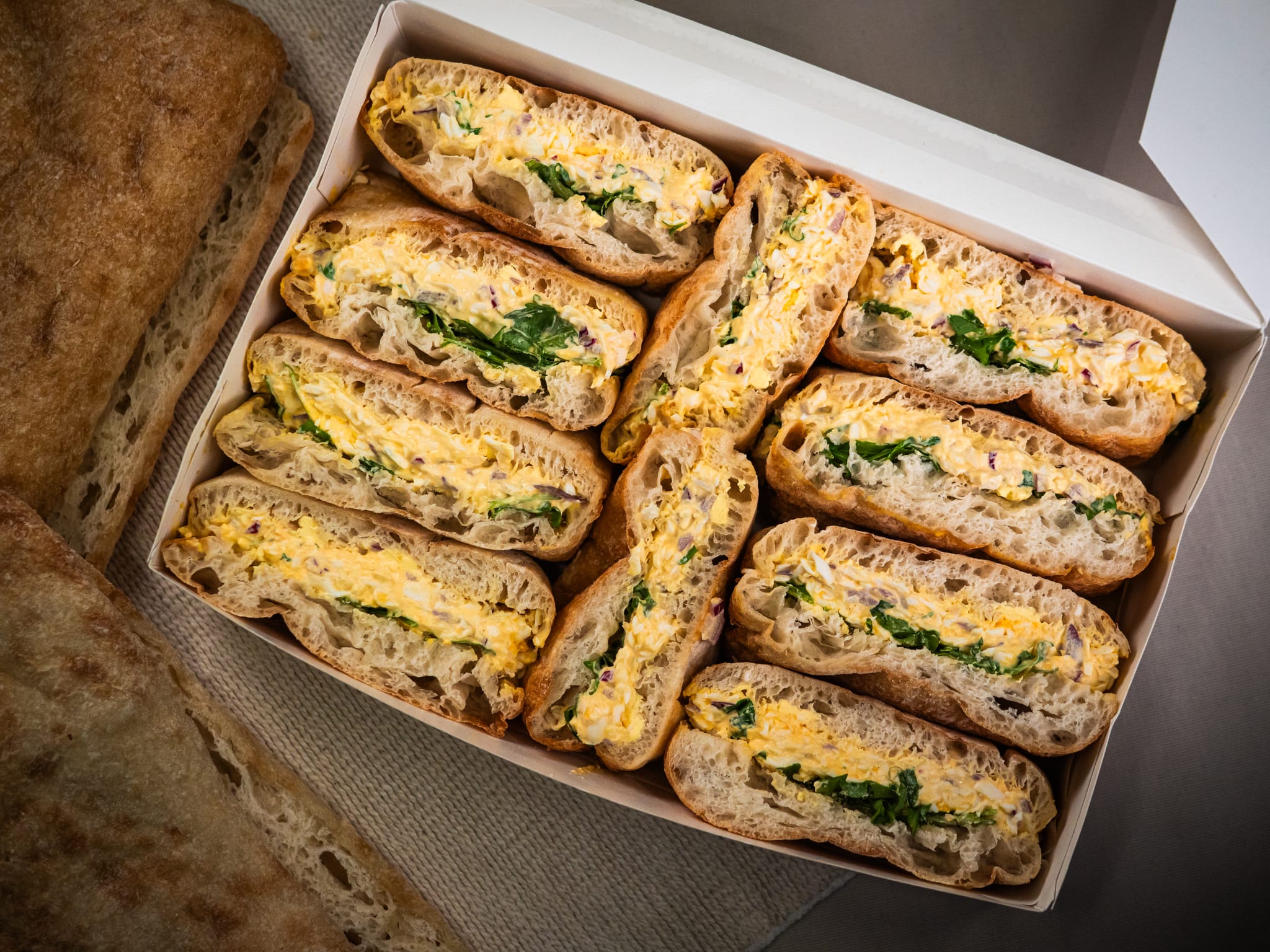 The Sub Side Mixed Sub Platter - 2 Full Boxes (serves 10) offers vegetarian sandwich halves with egg salad and leafy greens, arranged in rows—ideal for parties or group gatherings.