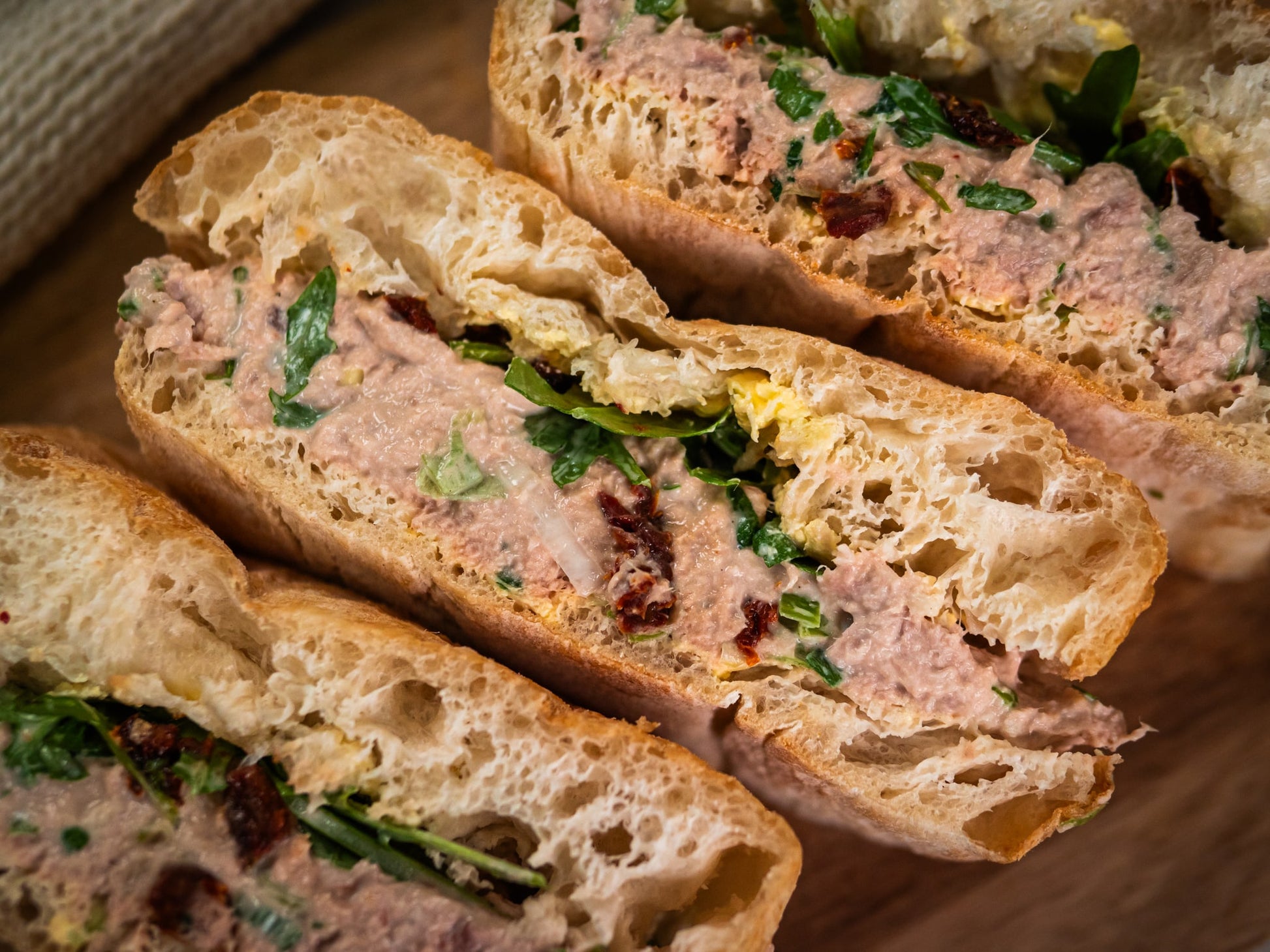 Close-up of Sub Side's Tuna Delight sandwiches, filled with lemon-Dijon tuna, peppery rocket, and sun-dried tomatoes on rustic bread.