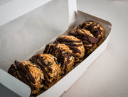 Six Sub Side Granola Bites Dark Chocolate, made with roasted oats and seeds and drizzled with dark chocolate, are arranged in a white box on a light surface—an ideal natural energy boost.