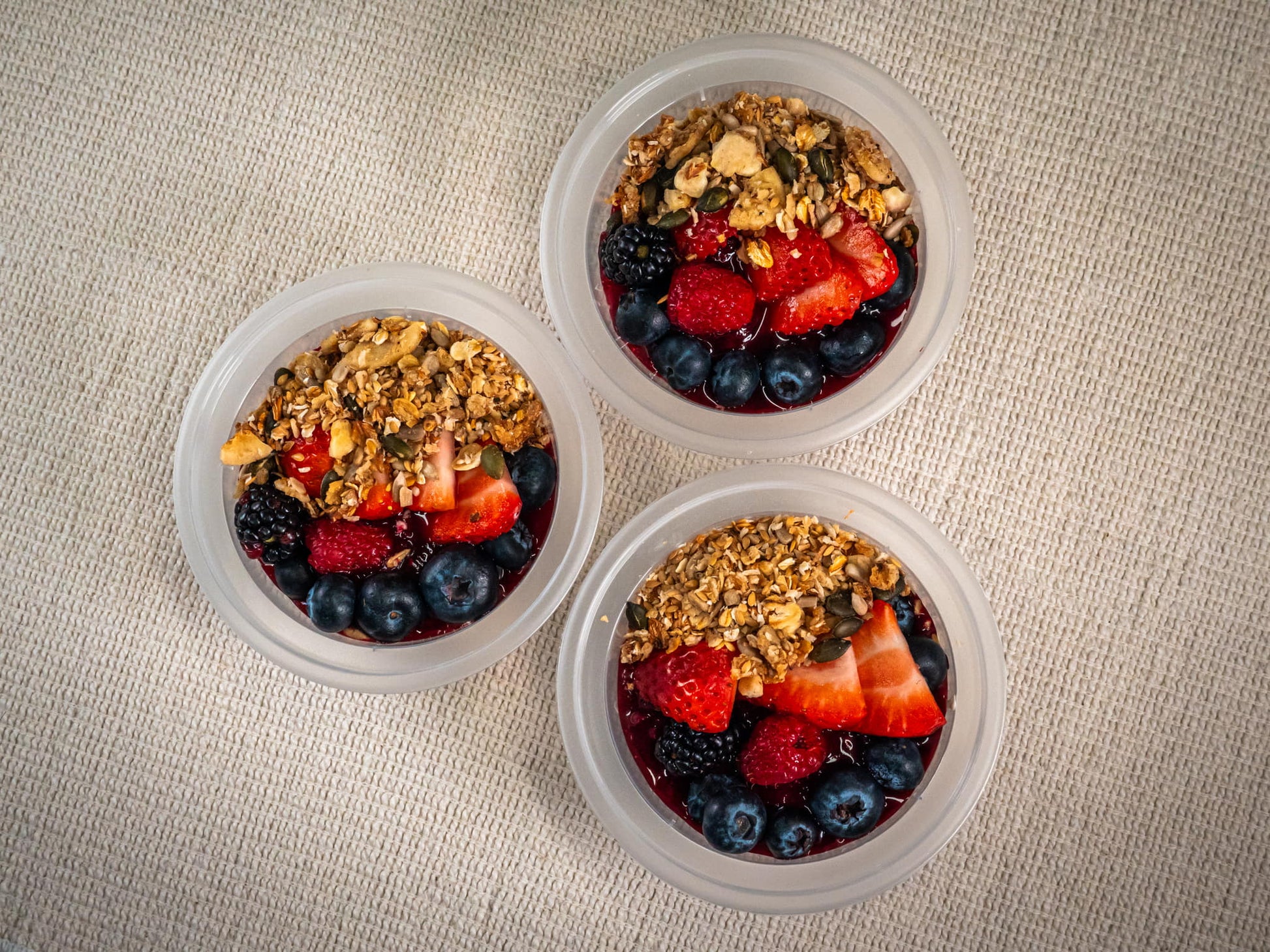Sub Side Yogurt Berry Snap Pot (227g) features Greek yogurt, homemade granola, strawberries, blueberries, blackberries, and seeds in three plastic cups on a beige textured surface.