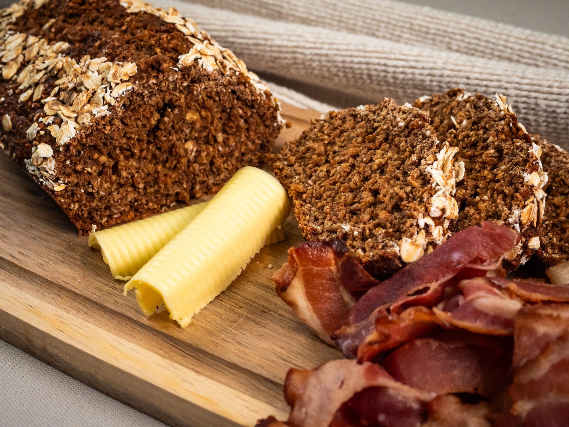 Sub Side’s Homemade Treacle Wheaten & Crispy Bacon (serves 5 pax) features sliced wheaten bread topped with crispy bacon and creamy butter, elegantly served on a wooden board.