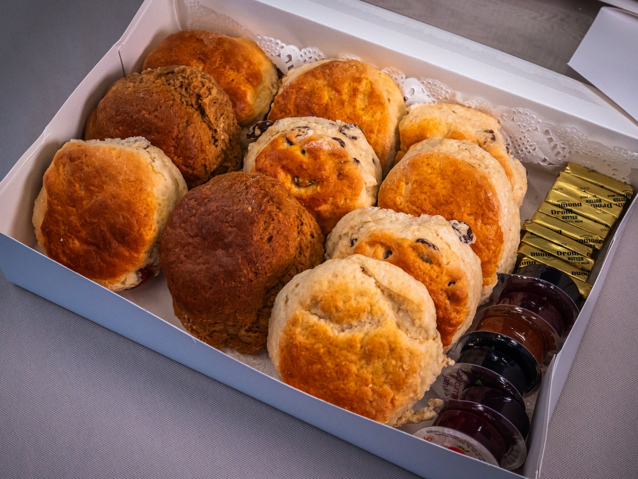 Sub Side's Freshly Baked Scones (10 pieces) come in a classic white box, including a mix of plain and fruit scones, with individual packets of butter and mini jars of fruit jam in the corner.
