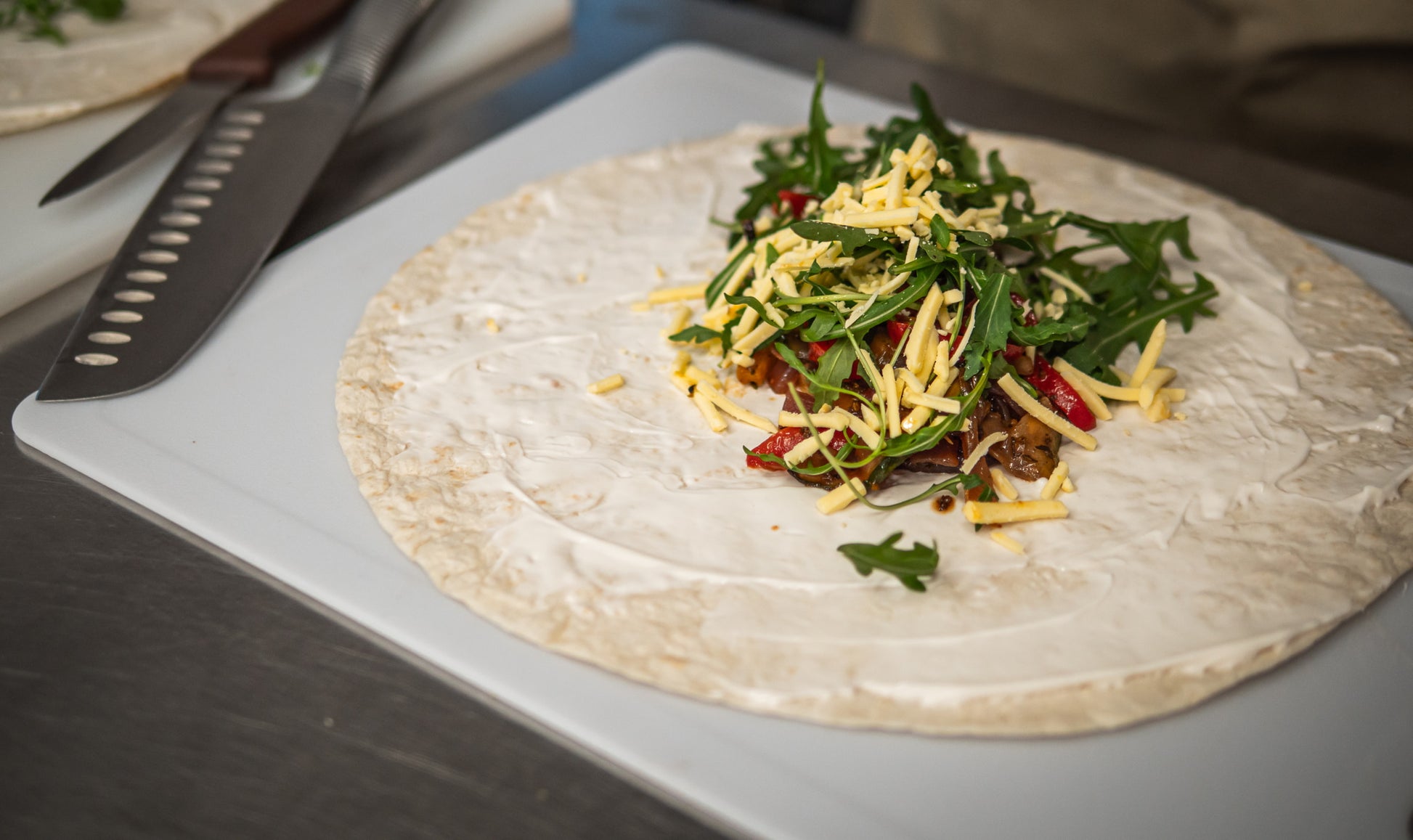 The Sub Side Mixed Wrap Platter (serves 7) features vibrant wraps topped with shredded cheese, arugula, and red peppers on a creamy spread—perfect for sharing and ready for your signature fillings.