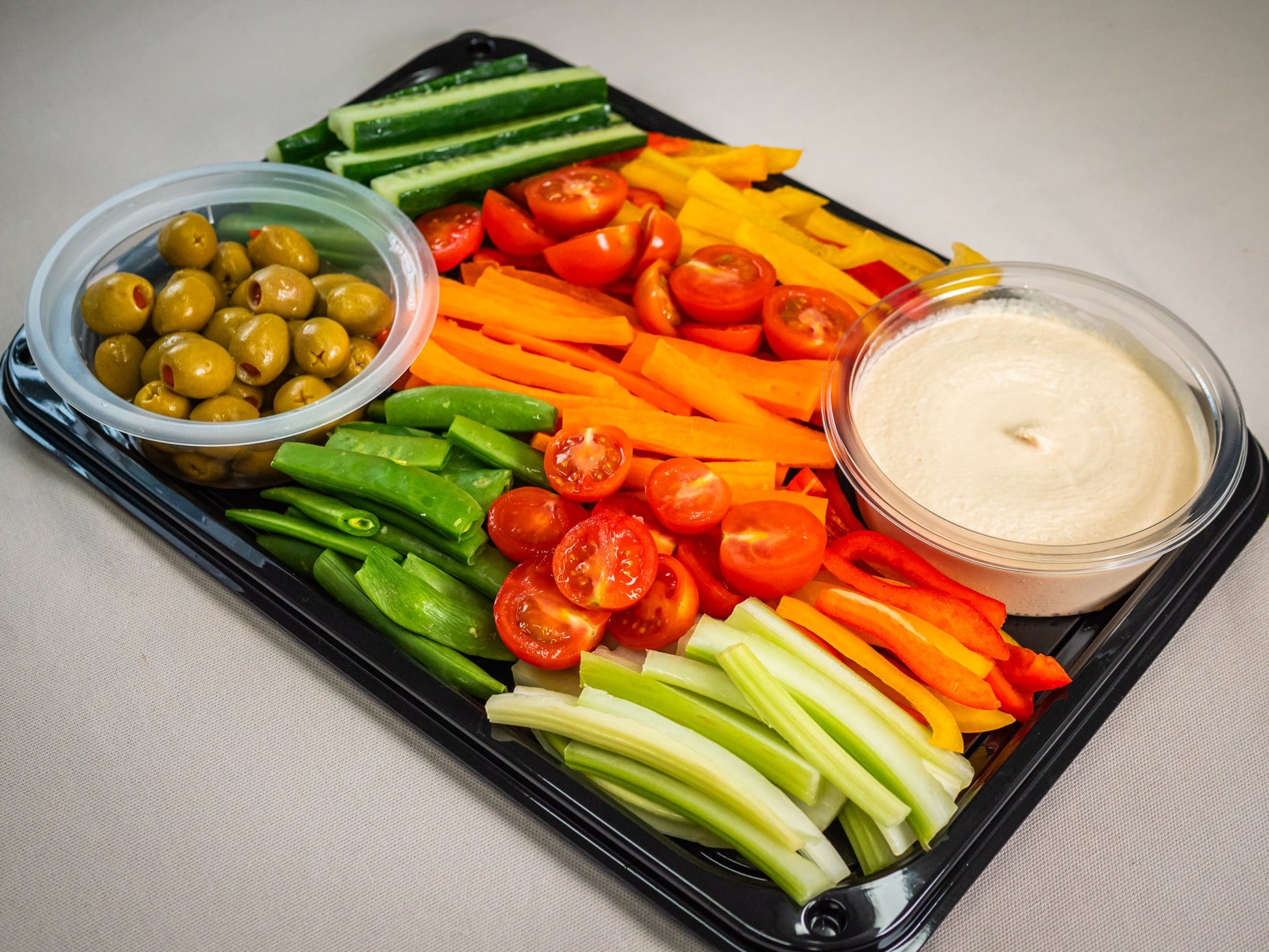 The Sub Side Garden Fresh Veggie Platter (serves 8) offers grape tomatoes, celery, bell peppers, snap peas, carrot sticks, cucumber slices, marinated olives, and creamy hummus for dipping.