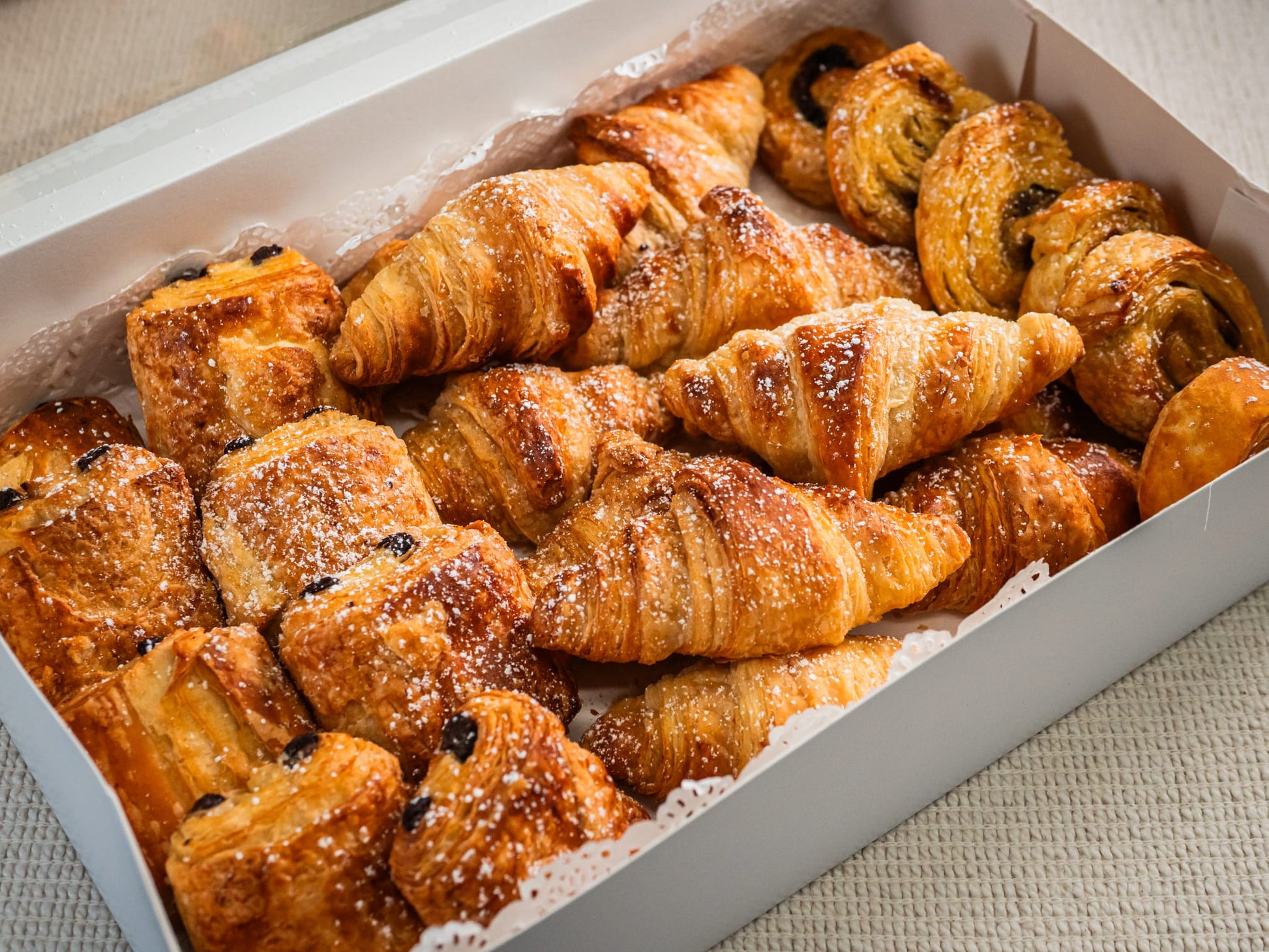Sub Side Assorted Mini Pastries (22 pieces), featuring butter croissants and pains au chocolat, neatly arranged in a white box on a light surface.