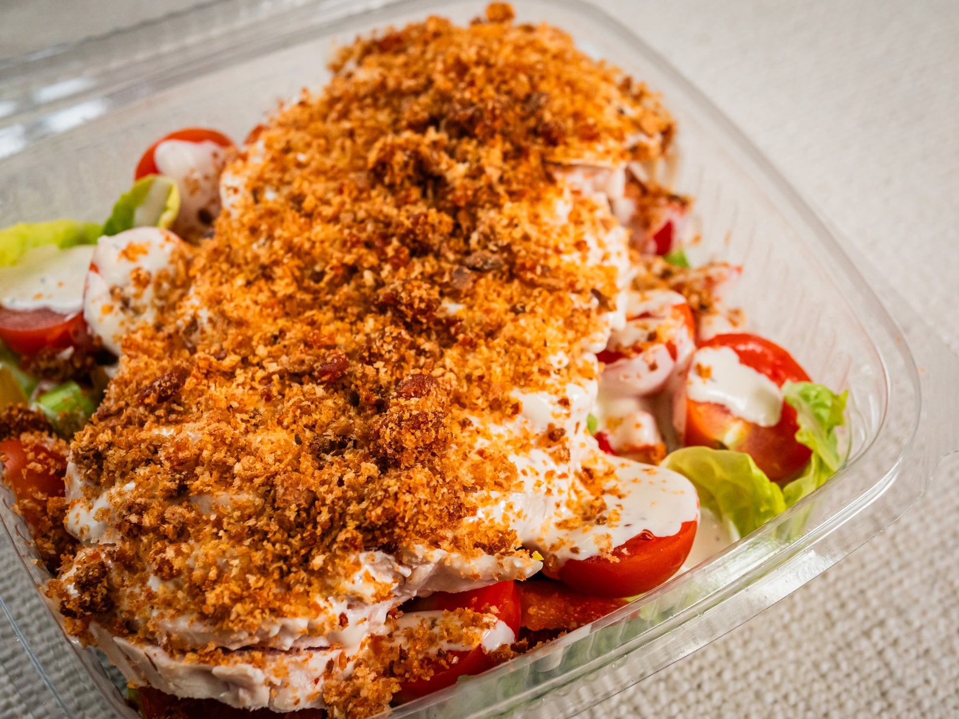Sub Side’s Sub Salad (400g) features crisp lettuce, sliced tomatoes, creamy caesar dressing, and a golden brown chorizo crumb in a plastic container.